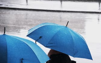 Passanti sotto la pioggia con ombrello aperto