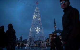 ISTANBUL, TURKEY - 2023/12/15: People pass by an illuminated Christmas tree made as part of end of year preparations in Taksim Square. (Photo by Onur Dogman/SOPA Images/LightRocket via Getty Images)
