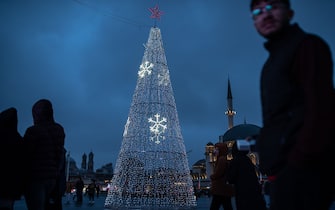 ISTANBUL, TURKEY - 2023/12/15: People pass by an illuminated Christmas tree made as part of end of year preparations in Taksim Square. (Photo by Onur Dogman/SOPA Images/LightRocket via Getty Images)