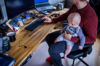 PRODUCTION - 10 May 2023, ---: A young father sits in his home office with his six-month-old son. Photo: Jens BÃ¼ttner/dpa (Photo by Jens BÃ¼ttner/picture alliance via Getty Images)