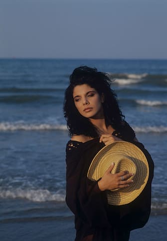 Portrait of Italian singer Mietta (Daniela Miglietta) holding a straw hat by the sea. 1990  (Photo by Angelo Deligio\Mondadori via Getty Images)