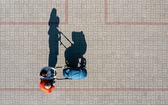 Aerial view of parent with a stroller on a walk during sunny day, perspective directly above