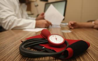 BERLIN, GERMANY - SEPTEMBER 05:  A doctor speaks to a patient as a sphygmomanometer, or blood pressure meter, lies on his desk on September 5, 2012 in Berlin, Germany. Doctors in the country are demanding higher payments from health insurance companies (Krankenkassen). Over 20 doctors' associations are expected to hold a vote this week over possible strikes and temporary closings of their practices if assurances that a requested additional annual increase of 3.5 billion euros (4,390,475,550 USD) in payments are not provided. The Kassenaerztlichen Bundesvereinigung (KBV), the National Association of Statutory Health Insurance Physicians, unexpectedly broke off talks with the health insurance companies on Monday.  (Photo by Adam Berry/Getty Images)