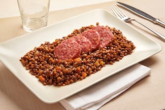 Cotechino and lentils, a traditional northern Italian dish of spicy pork sausage and brown lentils served on New Years Eve, on a rectangular platter