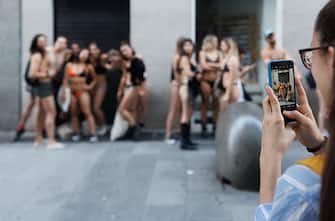 MADRID, SPAIN - JUNE 22: A woman photographs people queuing up to take part in Desigual's Seminaked event, at the Desigual store on Preciados street, June 22, 2023, in Madrid, Spain. Clothing brand Desigual has organized the 'Seminaked' event, in which it invites its first 100 customers to arrive at the store in their underwear, choose the two items they like best from the collection and wear them for free. (Photo By Eduardo Parra/Europa Press via Getty Images)