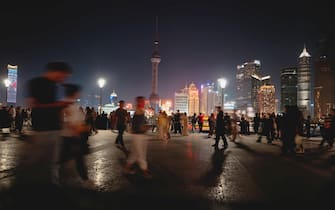 epa11981355 People walk on the Bund while Pearl TV Tower lights are dimmed during the Earth Hour, in Shanghai, China, 22 March 2025. Earth Hour takes place worldwide at 8.30 p.m. local time and is a global call to cut emissions by switching off lights for 60 minutes to raise awareness of the fight against global climatic change.  EPA/ALEX PLAVEVSKI