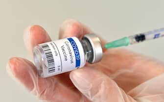 Coronavirus vaccine vial container in hand on white background. Close-up view. Coronavirus vaccine bottle.
