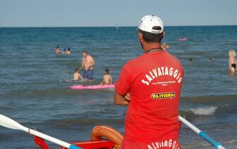 ASSISTENZA BAGNANTI IN SPIAGGIA A RIMINI. BAGNINO ACCANTO AL MOSCONE SALVATAGGIO IN RIVA AL MARE. (RIMINI - 2011-08-02, Francesco Campani / Fotogramma) p.s. la foto e' utilizzabile nel rispetto del contesto in cui e' stata scattata, e senza intento diffamatorio del decoro delle persone rappresentate