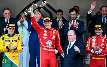 Ferrari's Monegasque driver Charles Leclerc (C-L) celebrates with the winner's trophy next to Prince Albert II of Monaco (C-R), second placed McLaren's Australian driver Oscar Piastri (L) and third placed Ferrari's Spanish driver Carlos Sainz (R) on the podium after the Formula One Monaco Grand Prix on May 26, 2024 at the Circuit de Monaco. (Photo by NICOLAS TUCAT / AFP) (Photo by NICOLAS TUCAT/AFP via Getty Images)