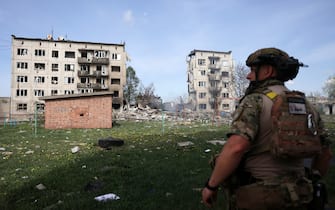 Officer of the special police force "White Angel" Hennadiy Yudin, 47, stands in front of apartment buildings destroyed by air bomb during the evacuation of local residents from the village of Ocheretyne not far from Avdiivka town in the Donetsk region, on April 15, 2024, amid the Russian invasion in Ukraine. (Photo by Anatolii STEPANOV / AFP)