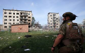 Officer of the special police force "White Angel" Hennadiy Yudin, 47, stands in front of apartment buildings destroyed by air bomb during the evacuation of local residents from the village of Ocheretyne not far from Avdiivka town in the Donetsk region, on April 15, 2024, amid the Russian invasion in Ukraine. (Photo by Anatolii STEPANOV / AFP)