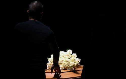 A person touches the coffin of late Italian fashion designer Giorgio Armani lying-in state for two days at the Armani Theatre in Milan, on September 6, 2025. Giorgio Armani died on September 4, 2025 at 91. (Photo by Stefano RELLANDINI / AFP)