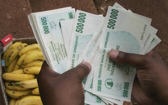 A Zimbabwean man counts a big stack of money to buy some bananas in Harare 23 January 2008 as the ongoing economical crisis in Zimbabwe leads to the world's highest rate of inflation. Zimbabwe's central bank governor Gideon Gono accused 22 January the local banks of creating artificial cash shortages by failing to collect new bank notes of 250,000, 500,000 and 750,000 Zim dollars, introduced 19 January, from the countrie's main bank and distribute it to clients. AFP PHOTO/ALEXANDER JOE (Photo credit should read ALEXANDER JOE/AFP via Getty Images)