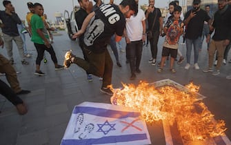 TOPSHOT - Iraqis burn Israeli flags during a rally held in central Baghdad on October 7, 2023 in support of the Palestinians, after Hamas militants launched a deadly air, land and sea assault into Israel from the Gaza Strip. (Photo by Murtadha Ridha / AFP) (Photo by MURTADHA RIDHA/AFP via Getty Images)