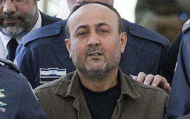 epa03077319 Handcuffed Palestinian Fatah leader Marwan Barghouti is escorted by Israeli police to the Magistrate Court in Jerusalem, 25 January 2012, after testifying in a US civil lawsuit against the Palestinian leadership. Barghouti, sentenced to life imprisonment in 2002 for being involved in anti-Israeli attacks when he led the Tanzim, a Fatah's militant faction, during the Second Intifada in 2000, was cited as saying that the Middle East conflict would only end only when Israel withdraws to the pre-1967 borderlines and a Palestinian state was established. Barghouti refused to testify in court today.  EPA/ABIR SULTAN