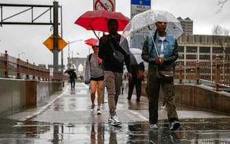 epa10890879 People walk across the Brooklyn Bridge in the heavy rain in New York, New York, USA, 29 September 2023. New York Governor Kathy Hochul declared a State of Emergency as flash flooding affects the New York City area due to heavy rain.  EPA/SARAH YENESEL