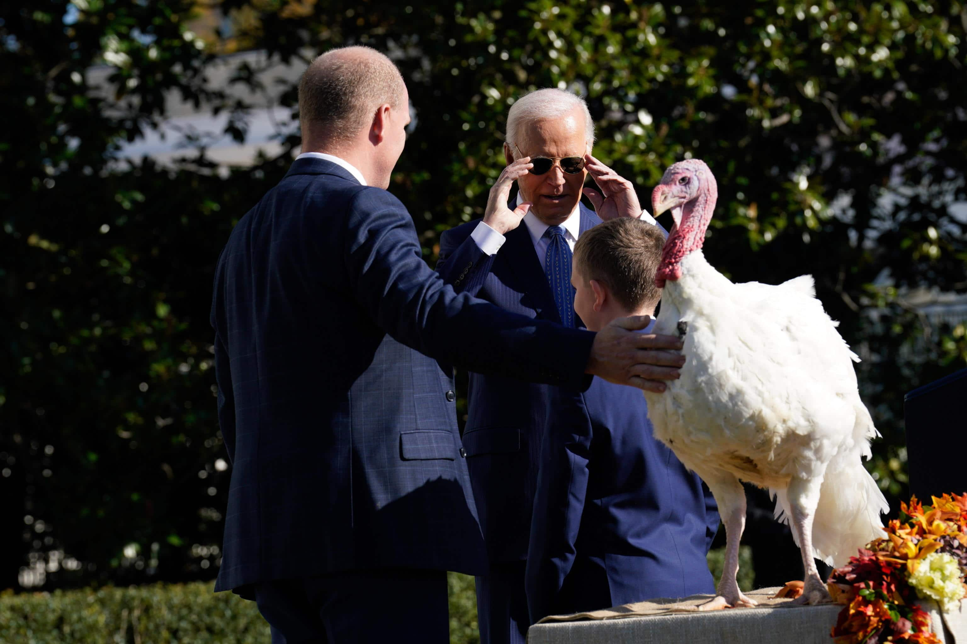 epa11740163 US President Joe Biden (C back) gestures next to chair of the National Turkey Federation John Zimmerman (L) and Zimmerman's son Grant (C front) as he pardons one of the two National Thanksgiving turkeys, Peach and Blossom from Minnesota, as part of the 77th annual National Thanksgiving Turkey presentation on the South Lawn of the White House in Washington, DC, USA, 25 November 2024.  EPA/YURI GRIPAS/POOL