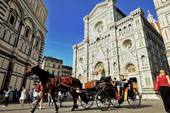 Tourists on a carriage pass in front of Cathedral of Santa Maria del Fiore on May 26, 2018 in central Florence. (Photo by ANDREAS SOLARO / AFP)        (Photo credit should read ANDREAS SOLARO/AFP via Getty Images)