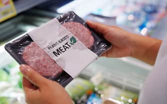 Close-up hand carry choose zero pork soy bean faux peas cutlet gluten free read beyond non-meat lab label. Buy raw fake beef tray in asia store veggie burger patty for health care eat diet meal cook.