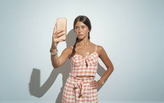 Fashionable Young woman take a selfie against blue background.Studio shot