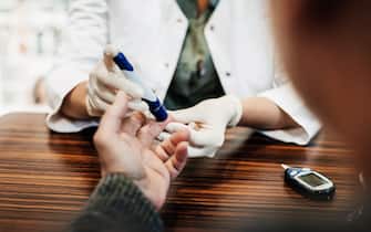 A pharmacist checking a customers blood sugar levels with an insulin pen.