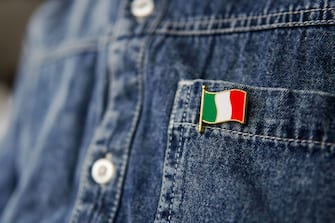 Metal badge with the flag of Italy is pinned on blue jeans jacket. Italy patriotism concept. Independence Day Holiday in Italy.