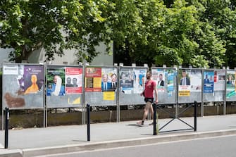 epa10018605 A man walks past posters for the second round of the legislative elections, in Bordeaux, France, 17 June 2022. The second round of the French legislative elections will take place on 19 June 2022.  EPA/CAROLINE BLUMBERG