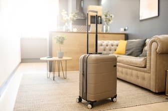 Contemporary plastic suitcase prepared for journey placed on floor in living room at home