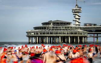 epa10385225 People run into the sea at the beach of Scheveningen on New Year's Day, Scheveningen, Netherlands, 01 January 2023. The traditional New Year's dive was resumed after the two previous editions were canceled due to the corona crisis.  EPA/REMKO DE WAAL