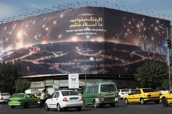 epa11684280 Iranians drive past an anti-Israel billboard depicting Iran's recent missile attack on Israel and a sentence reading in Persian 'If you want war, we are the master of war', at the Enghelab square in Tehran, Iran, 26 October 2024. Israel Defense Forces (IDF) spokesman Daniel Hagari confirmed on 26 October that the Israeli Army, Tsahal, conducted precise strikes on military targets in Iran. According to the Iran Air Defense Force, the Israeli attack was successfully countered by the country's integrated air defense system.  EPA/ABEDIN TAHERKENAREH