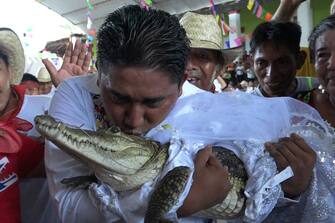 TOPSHOT - Victor Hugo Sosa, Mayor of San Pedro Huamelula, kisses a spectacled caiman (Caiman crocodilus) called "La NiÃ±a Princesa" ("The Princess Girl") before marrying her in San Pedro Huamelula, Oaxaca state, Mexico on June 30, 2023. This ancient ritual of more than 230 years unites two ethnic groups in marriage to bring prosperity and peace. The spectacled caiman (Caiman crocodilus) is paraded around the community before being dressed as a bride and marrying the Mayor. According to beliefs, this union between the human and the divine will bring blessings such as a good harvest and abundant fishing. (Photo by RUSVEL RASGADO / AFP) (Photo by RUSVEL RASGADO/AFP via Getty Images)