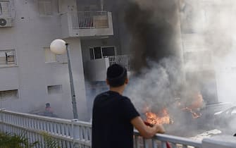 A resident looks at cars burning after a during a rocket attack in Ashqelon, Israel, on Saturday, Oct. 7. 2023. Israel declared a rare state of alert for war on Saturday after militants fired an estimated 2,200 missiles from the Gaza Strip and infiltrated southern parts of the country. Photographer: Kobi Wolf/Bloomberg via Getty Images