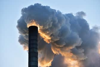 Industrial smoking chimney, against clear sky at sunset.