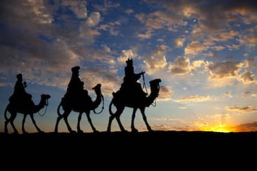 The three kings on camels against a setting sun.