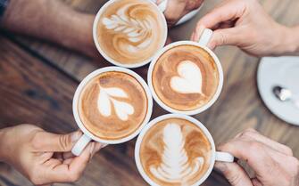Above view of hands holding cappuccino cups