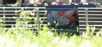 Un senza fissa dimora riposa su una panchina a Milano, 19 maggio 2021. ANSA/DANIEL DAL ZENNARO