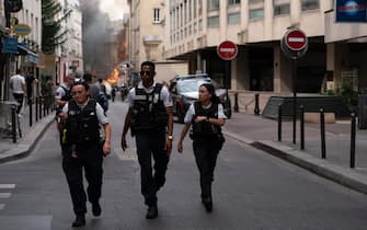 French police officers walk after a building partly collapsed at Place Alphonse-Laveran in the 5th arrondissement of Paris, on June 21, 2023. A major fire broke out on June 21, 2023 in a building in central Paris, part of which collapsed, according to images taken by AFP journalists. (Photo by ABDULMONAM EASSA / AFP) (Photo by ABDULMONAM EASSA/AFP via Getty Images)