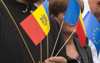 epa03839046 A priest is holding flags of Moldova, Romania and EU at opening of construction of Iashi-Ungheni Moldo-Romanian pipeline on Zagarancea village at Ungheni district, 137 Km North-West Moldova on 27 August 2013.  EPA/DUMITRU DORU