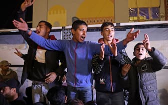 People celebrate while watching a television along a street in Khan Yunis in the southern Gaza Strip on January 15, 2025, amid the ongoing war in the Palestinian territory between Israel and Hamas. Thousands of Gazans celebrated on January 15 as news spread that a ceasefire and hostage release deal had been reached between Israel and Hamas, aimed at ending more than 15 months of war in the Palestinian territory. (Photo by BASHAR TALEB / AFP)