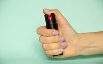 Woman's hand holding a pepper spray on an isolated background, self-defense, safety