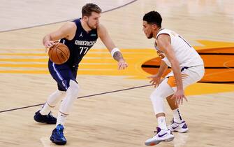 PHOENIX, ARIZONA - DECEMBER 23: Luka Doncic #77 of the Dallas Mavericks controls the ball against Devin Booker #1 of the Phoenix Suns during the NBA game at PHX Arena on December 23, 2020 in Phoenix, Arizona.  The Suns defeated the Mavericks 106-102.  NOTE TO USER: User expressly acknowledges and agrees that, by downloading and/or using this Photograph, user is consenting to the terms and conditions of the Getty Images License Agreement. (Photo by Christian Petersen/Getty Images)