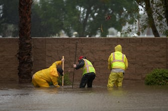 epa10811209 Public works employees try to unclog a drain due to flooding as Tropical Storm Hilary arrives in Rancho Mirage, California, USA, 20 August 2023. Southern California is under a tropical storm warning for the first time in history as Hilary makes landfall. The last time a tropical storm made landfall in Southern California was 15 September 1939, according to the National Weather Service.  EPA/ALLISON DINNER