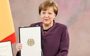 epa10577210 Former German Chancellor Angela Merkel poses with the box after she was awarded the 'Grand Cross of the Order of Merit of the Federal Republic of Germany' by German President Frank-Walter Steinmeier during a ceremony in Berlin, Germany, 17 April 2023.  EPA/FILIP SINGER