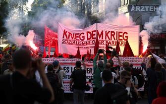 epa11312892 Protesters light flares and hold a banner reading 'War to the war' during the Revolutionary May Day Demonstration in Berlin, Germany, 01 May 2024. The traditional Revolutionary May Day Demonstration takes place in the districts of Kreuzberg and Neukoelln in 2024. Labor Day, or May Day, is observed all over the world on the first day of May to celebrate the economic and social achievements of workers and advocate for their rights.  EPA/CLEMENS BILAN