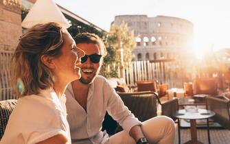 Romantic couple smiling at sunset in Rome, Italy. Colosseum in background