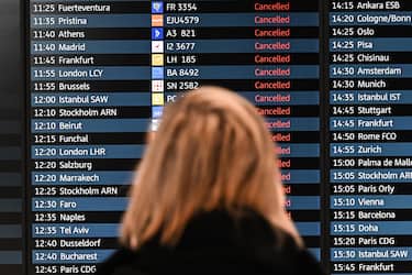 epa10519573 A passenger looks at an electronic board showing canceled flights at the Berlin-Brandenburg airport, Germany, 13 March 2023. The employees of aviation security and ground handling services called for a 24 hours strike over wages.  EPA/FILIP SINGER