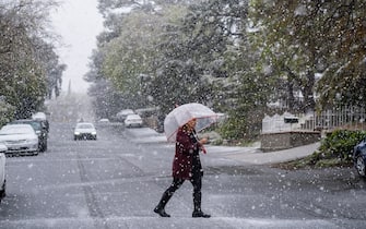 Glendale, CA - February 25:  Leslie Whelan of Glendale steps outside her home to check out the snow falling on Saturday afternoon, Feb. 25, 2023, in Glendale, CA. A historic winter storm slamming California with heavy rains, dangerous winds and rare snowfall intensified Friday as it moved south, shutting down mountain freeways and prompting severe weather warnings not often seen in the region. (Francine Orr / Los Angeles Times via Getty Images)