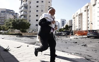 A man runs past cars damaged during a rocket attack in Ashqelon, Israel, on Saturday, Oct. 7. 2023. Israel declared a rare state of alert for war on Saturday after militants fired an estimated 2,200 missiles from the Gaza Strip and infiltrated southern parts of the country. Photographer: Kobi Wolf/Bloomberg via Getty Images
