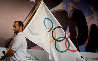 An employee carries the Olympic flag before the Intenational Olympic Commitee (IOC) debriefing of the London 2012 Olympic Games for the foreing press in Barra de Tijuca, Rio de Janeiro, Brazil on November 21, 2012.  AFP PHOTO/Christophe Simon        (Photo credit should read CHRISTOPHE SIMON/AFP via Getty Images)