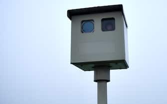 A traffic enforcement camera, speed camera, road safety camera, photo radar or flash for cash. Overcast sky.